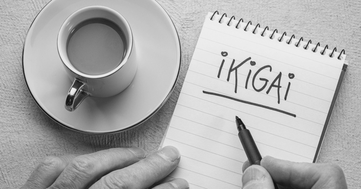 Copo de café ao lado de um bloco de notas com a palavra Ikigai escrita.