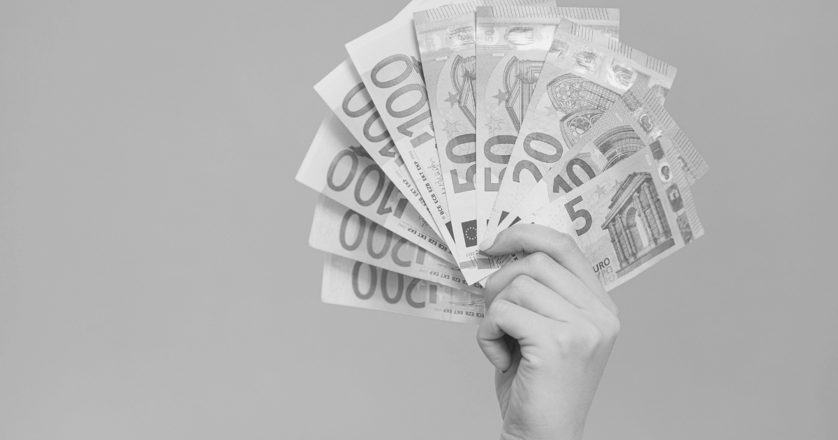 Mão segurando várias notas de euro, simbolizando definição de preços.